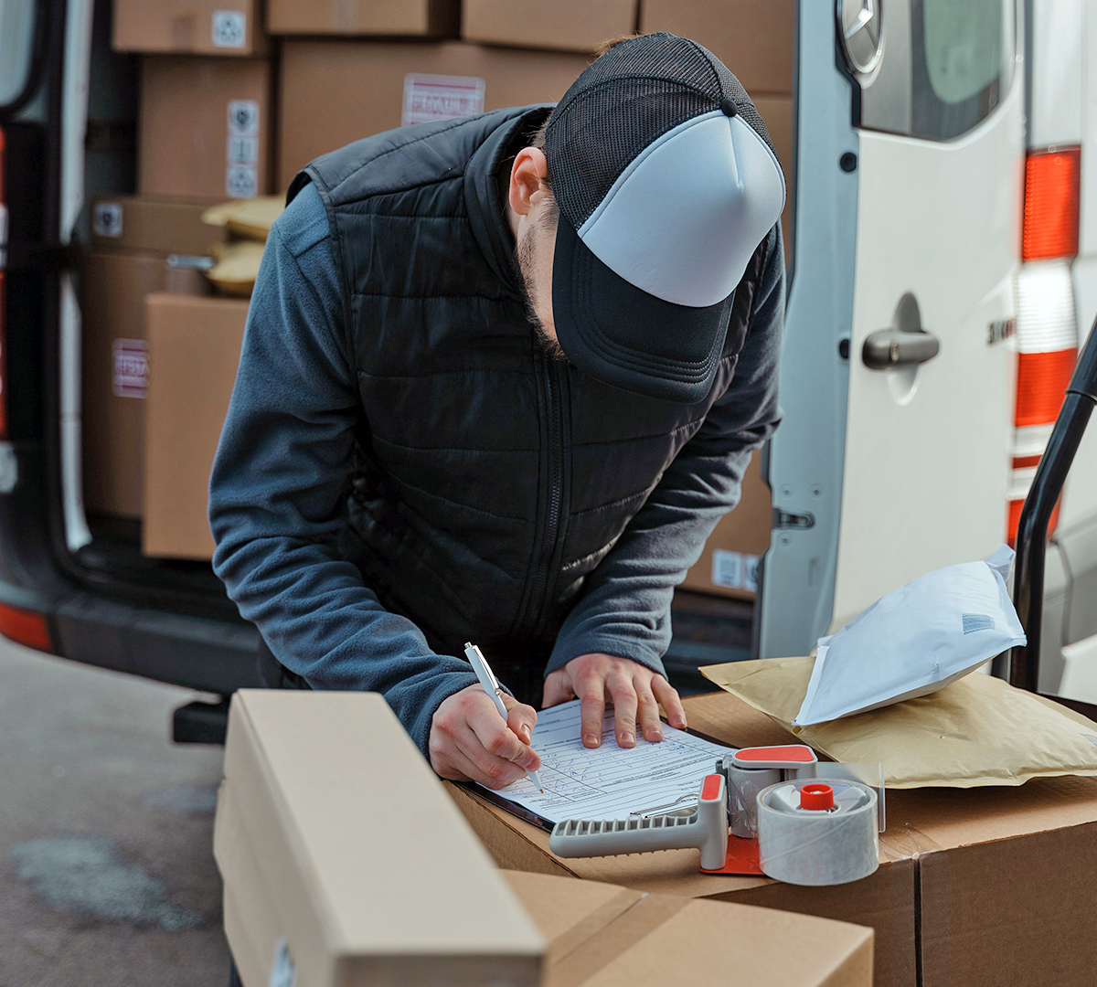 Man filling out paperwork on top of shipping packages